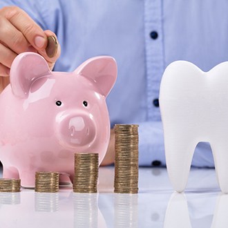 tooth and piggy bank for cost of dental implants in Zionsville 
