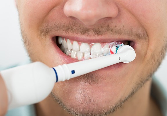 Man brushing teeth to maintain porcelain veneers