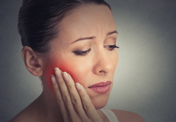 Woman in need of emergency dentistry holding cheek in pain