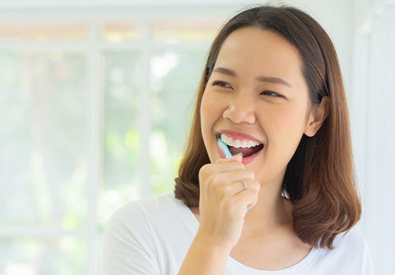 Woman brushing teeth to prevent dental emergencies