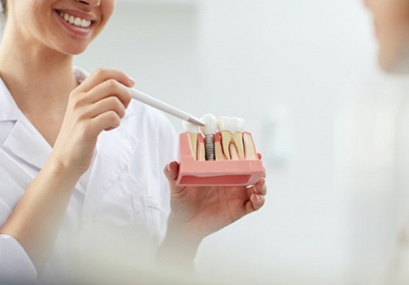 A dental implant dentist in Zionsville showing a patient how dental implants work