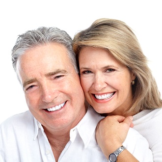 An older couple hugging and smiling after receiving dental implants in Zionsville