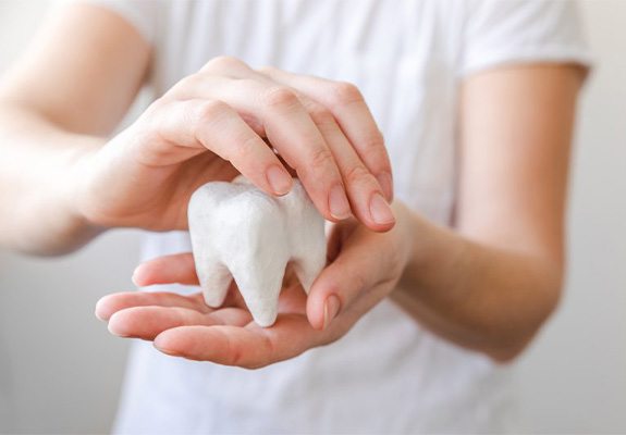 Patient holding a giant plaster model of a tooth