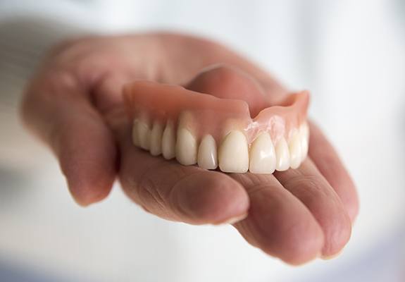 Hand holding dentures