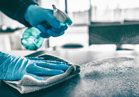 Dental team member sanitizing dental office