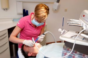 dental hygienist pink shirt cleaning teeth