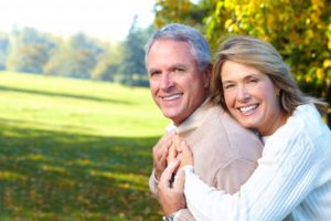 An older couple hugging and smiling outside.