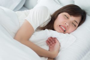 a woman clenching her teeth while asleep