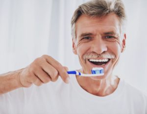 an older man brushing his teeth