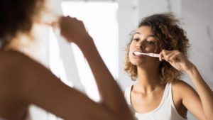 person brushing their teeth and taking care of their dental crowns