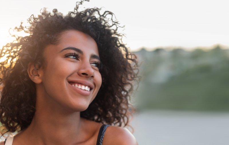 a young female standing outside while looking off into the distance and smiling