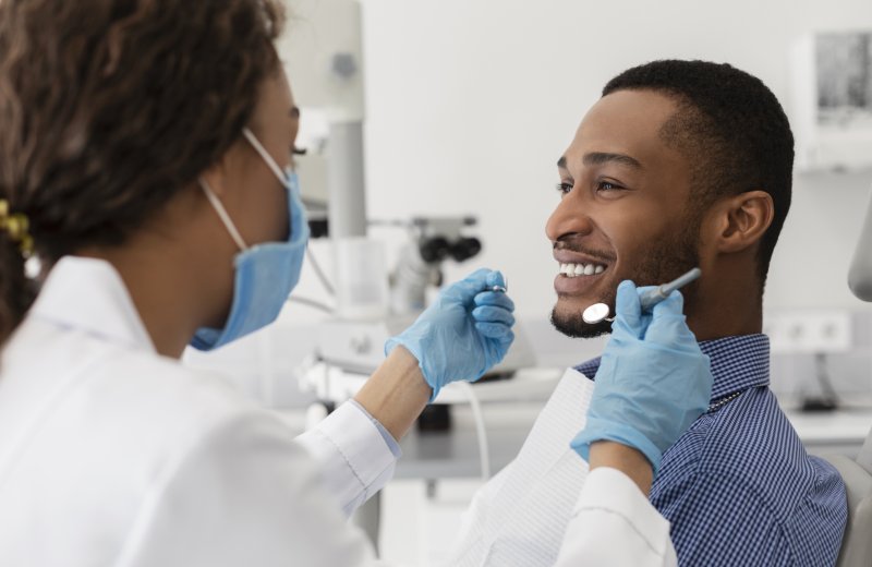 a dentist in Zionsville examining a male patient’s smile during a visit