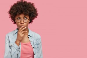 Woman on pink background wondering about cosmetic dental treatments