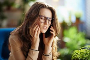 Woman with toothache calling an emergency dentist